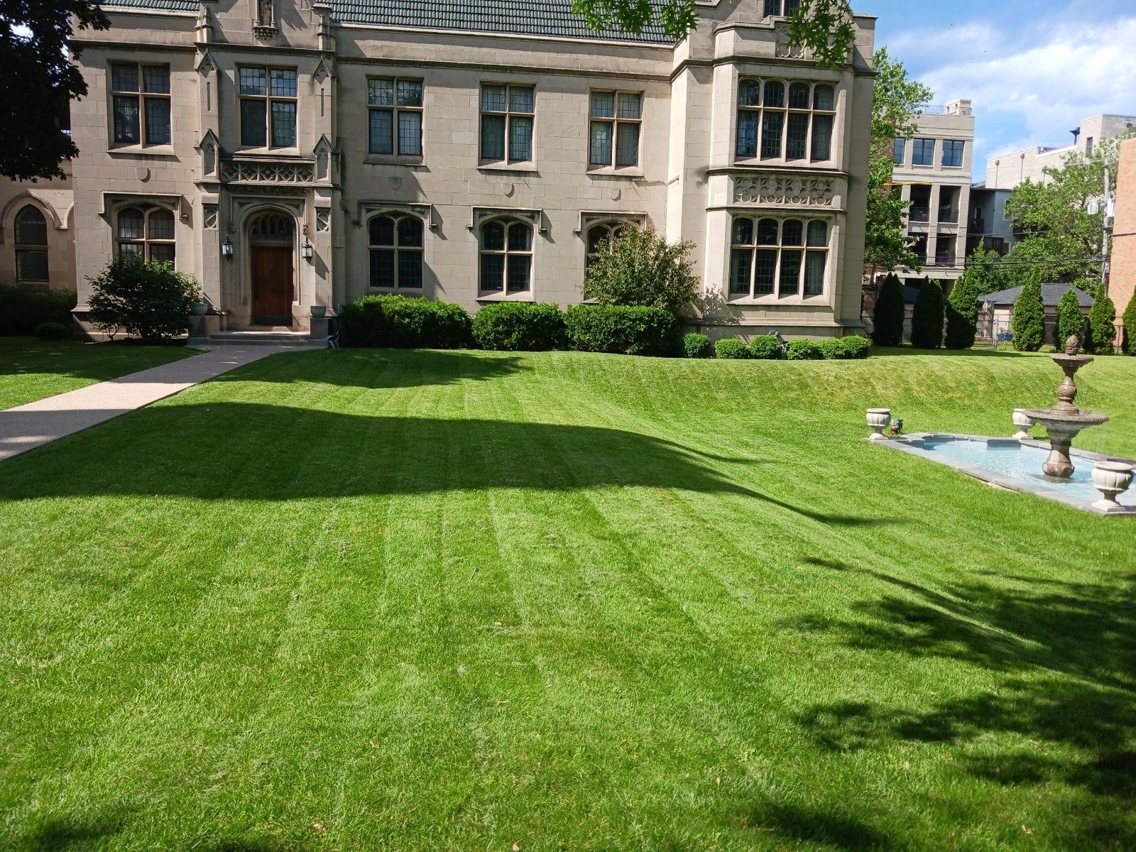 Lawn Pushers striped mowing on a premium Chicago property with fountain — same crew, spring through fall